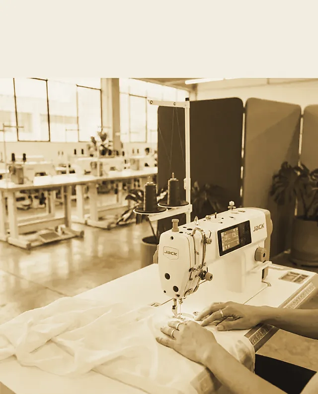 Maños guiando la tela bajo la aguja de una máquina industrial